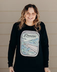 Unisex recycled long sleeve black shirt with Dreamin' airplane design on front and text on back