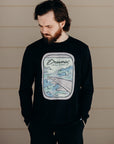Unisex recycled long sleeve black shirt with Dreamin' airplane design on front and text on back