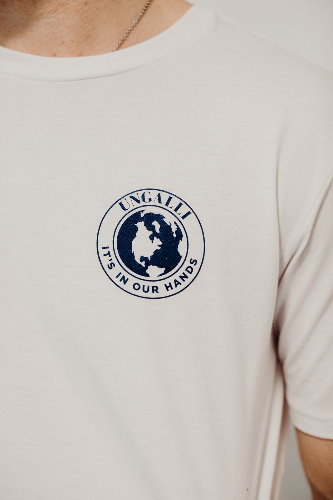 White organic short sleeve unisex t-shirt with blue "it's in our hands" Ungalli logo on front and across back