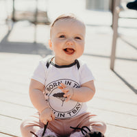 Organic baby onesie in white with grey "Born in Tbay" logo on front