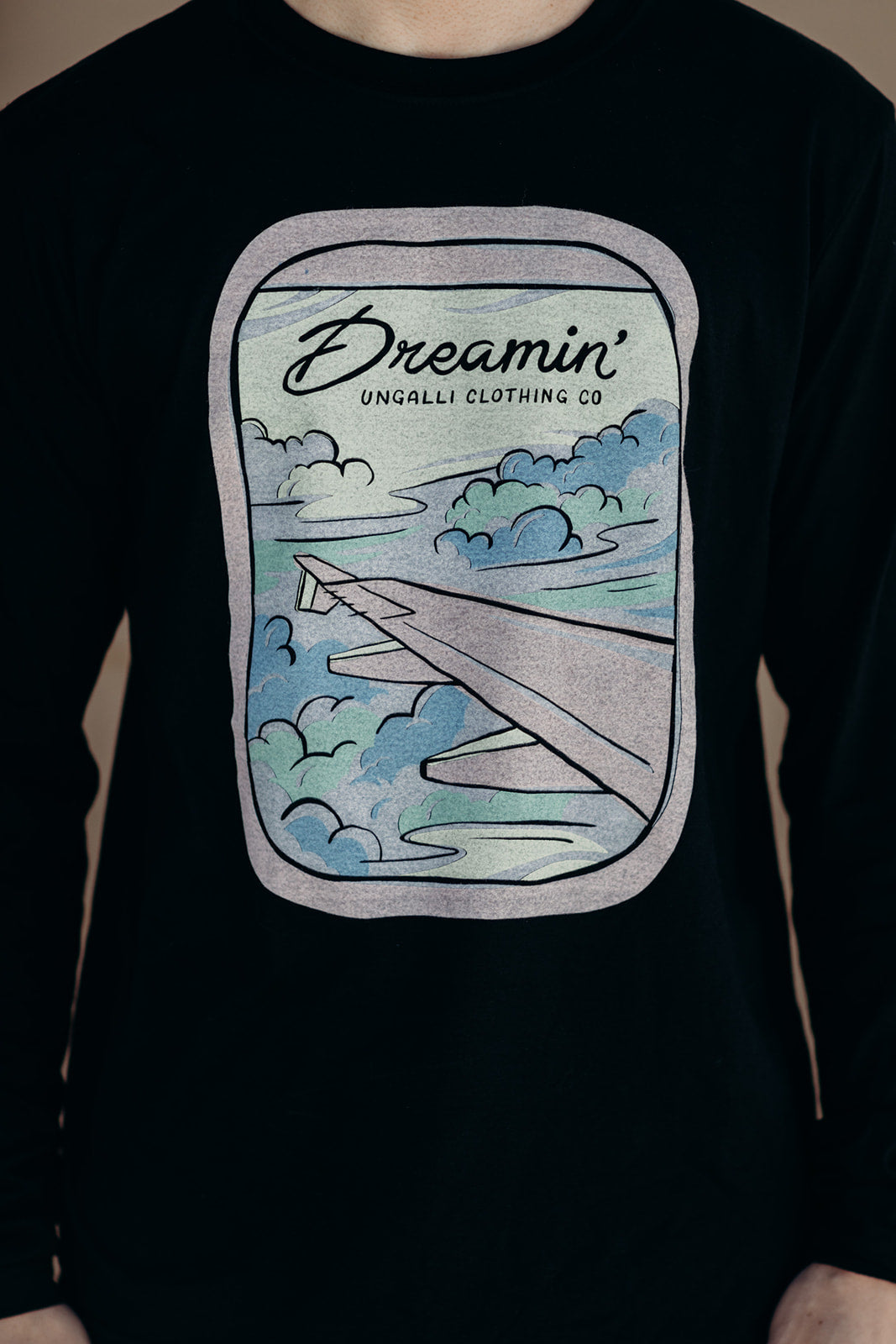 Unisex recycled long sleeve black shirt with Dreamin' airplane design on front and text on back