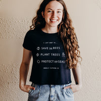Women's organic black cropped t-shirt with text on front that reads: "I just want to save the bees, plant trees & protect our seas"