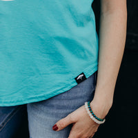 Women's organic teal tank top with white 'adventure club' logo