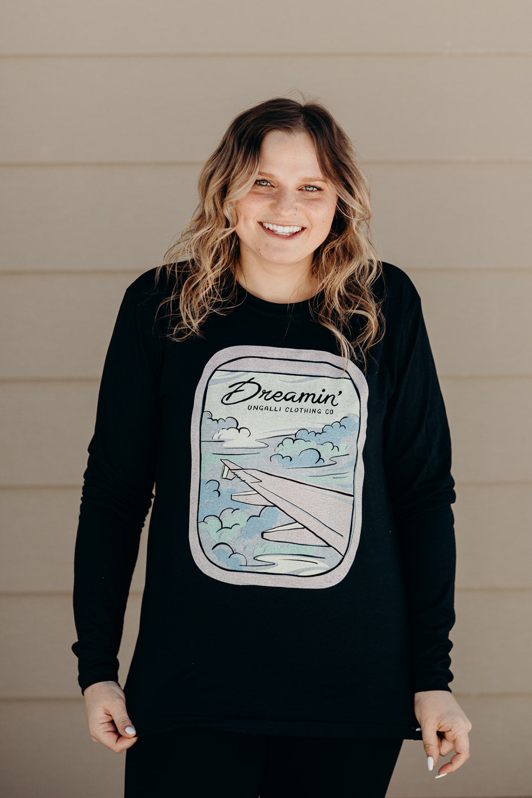 Unisex recycled long sleeve black shirt with Dreamin' airplane design on front and text on back