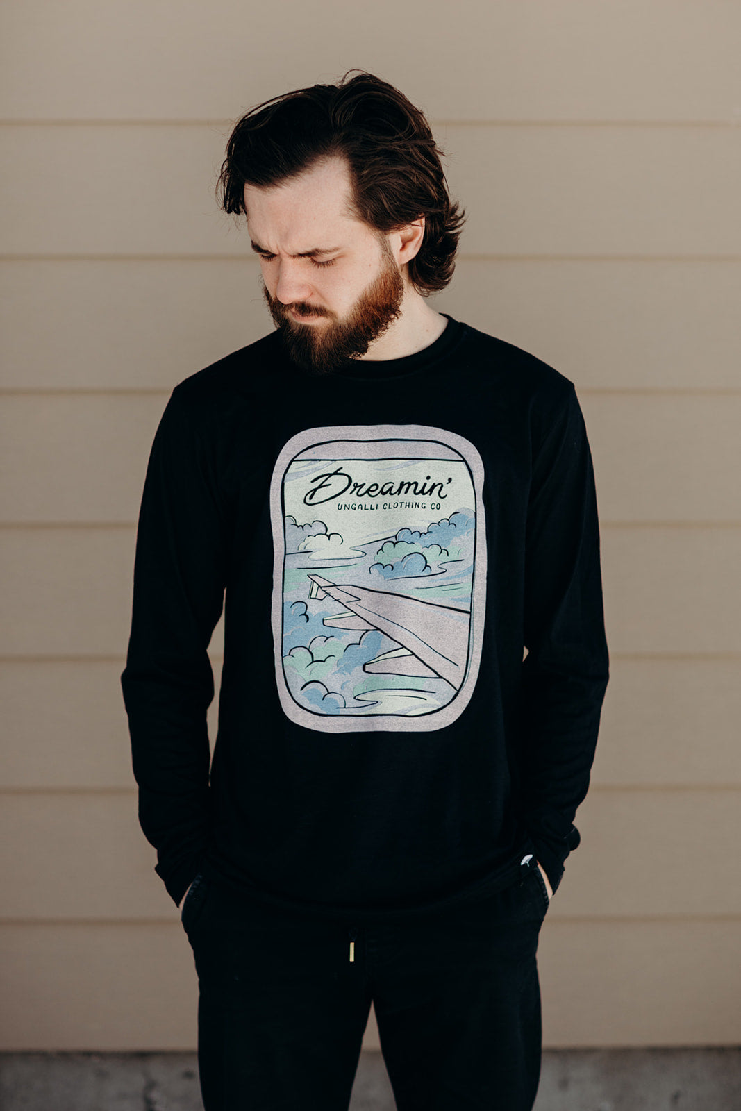 Unisex recycled long sleeve black shirt with Dreamin' airplane design on front and text on back