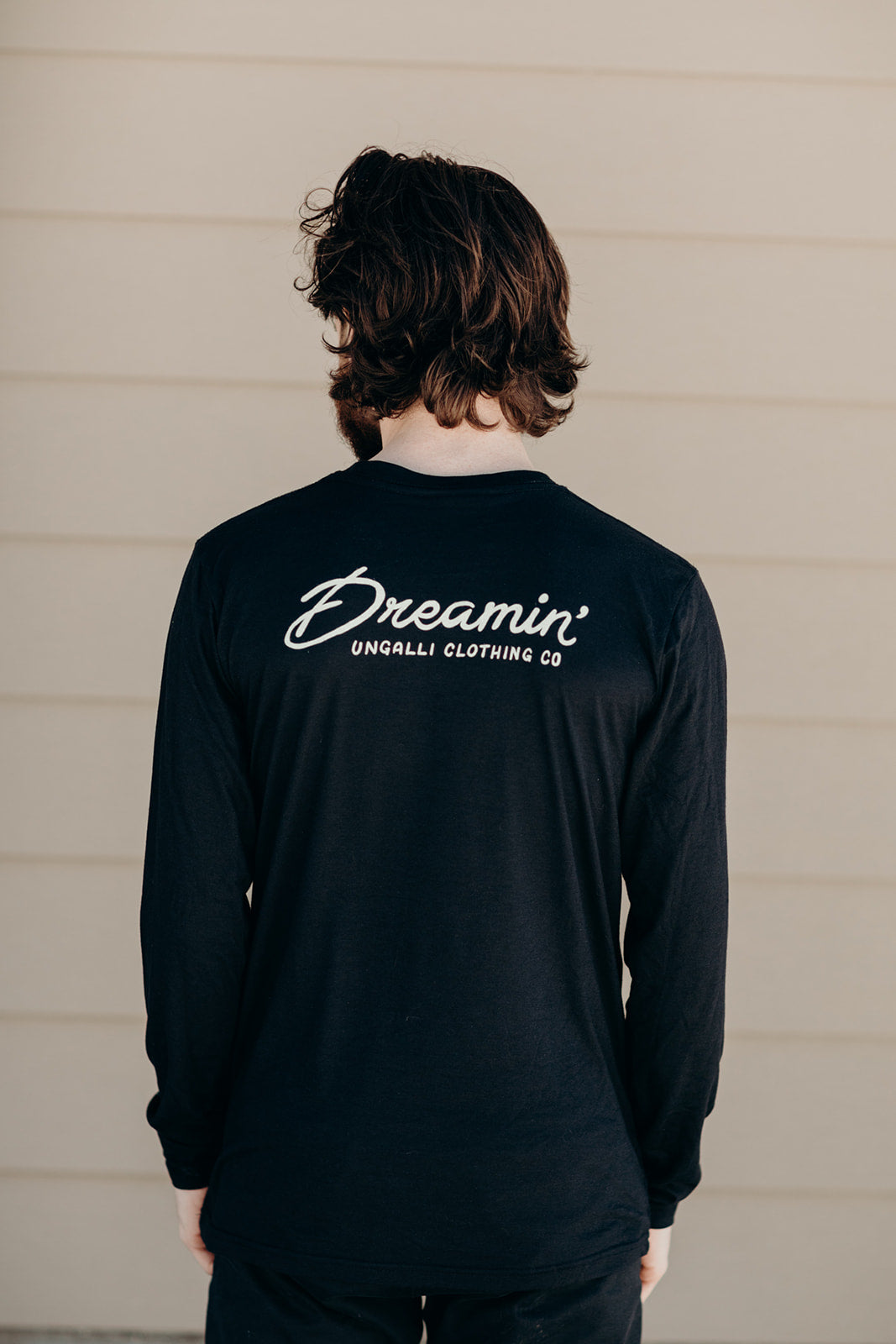 Unisex recycled long sleeve black shirt with Dreamin' airplane design on front and text on back