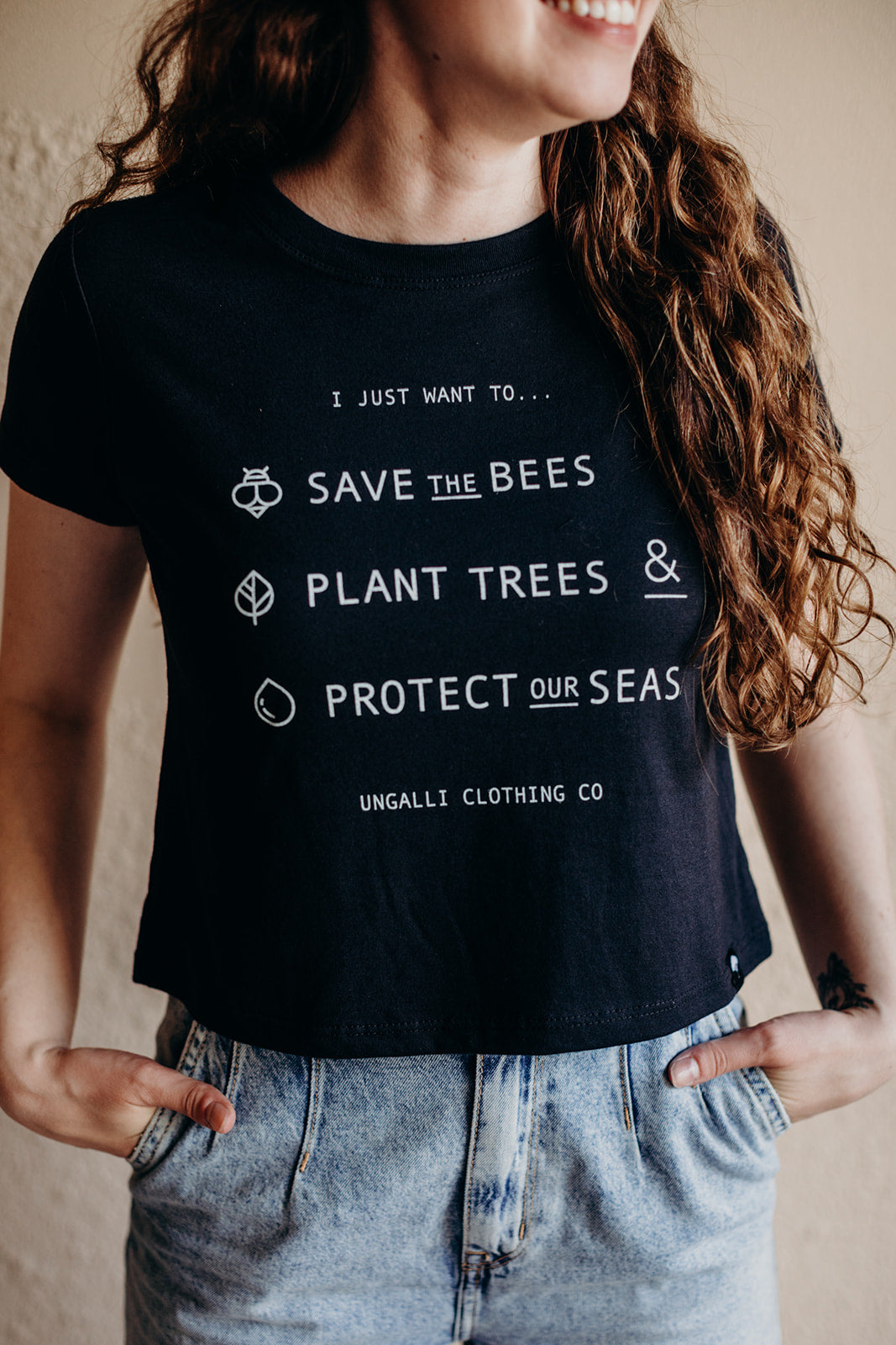 Women's organic black cropped t-shirt with text on front that reads: "I just want to save the bees, plant trees & protect our seas"